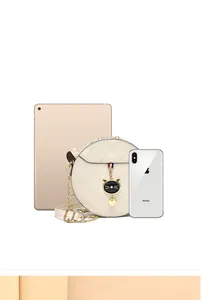 Quilted round crossbody bag size comparison with tablet and phone in cream white