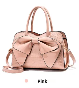 Detailed view of pink glossy faux crocodile leather handbag with decorative bow