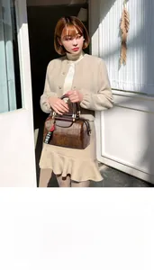 Detail of a dark brown crocodile embossed satchel bag with stylish heart charm accessory