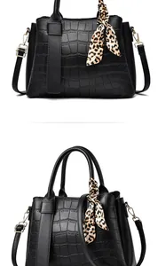 Close-up of black crocodile pattern handbag featuring gold hardware and leopard silk scarf