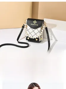 Détail du mini sac bandoulière matelassé avec poignée perle et logo doré