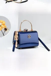 Close-up of deep blue patent leather handbag with golden ring handle and rhinestone clasp