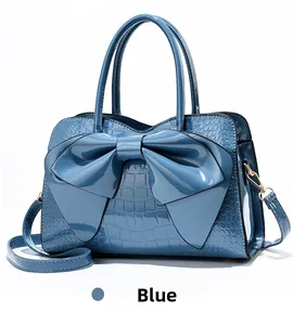 Detail of blue faux crocodile pattern patent leather handbag with large decorative bow