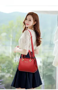 Elegant red leather handbag with gold hardware shown on a model in a bright room