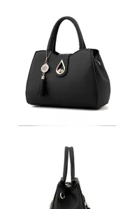 Close-up of black pebbled leather handbag featuring gold teardrop lock and tassel detail