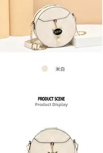 Detail of off-white quilted round crossbody bag with golden chain and cat charm pendant