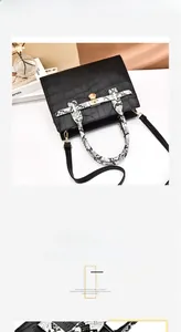 Detail of crocodile embossed leather bag featuring a gold metal lock and snake pattern strap