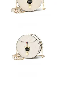 Close-up of cream quilted round crossbody bag with gold chain and cat pendant charm