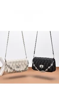 Detail of pleated shoulder bags in black and cream with rhinestone chains and metal locks