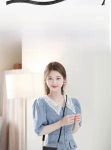 Mini sac bandoulière en cuir noir avec fermoir fleur dorée porté par un modèle