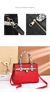 Detail of red crocodile textured leather bag with gold lock and snake skin pattern handles