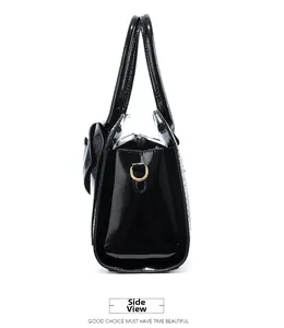 Side view of shiny black patent leather handbag featuring gold metal D-ring attachment