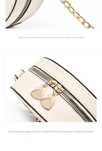 Close-up of gold chain strap and dual zipper detail on off-white leather round bag