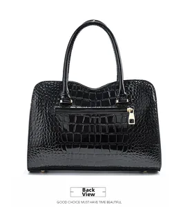 Detail of black crocodile embossed patent leather handbag with gold zipper and back pocket