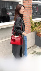 Détail du sac à main en PU rouge matelassé avec poignée dorée et breloque pompon