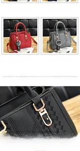 Detail of lychee pattern leather handbag with metallic hardware and fuzzy ball charm