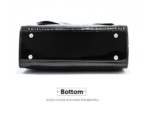 Detail of glossy black patent leather bag bottom with golden metal feet and croc pattern