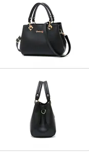 Detail view of black lychee leather handbag with golden hardware and branding