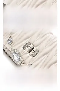 Detail of wave quilted cream leather bag with crystal rotary lock and jewel chain