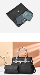 Macro detail of black crocodile leather handbag set with snake print handles and gold hardware