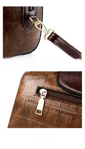 Close-up of golden hardware and zipper on brown crocodile textured leather handbag