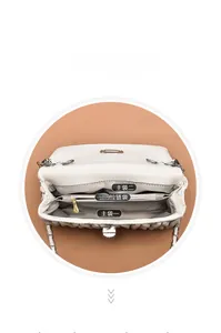 Detailed interior of beige quilted handbag showing three compartments and gold zipper