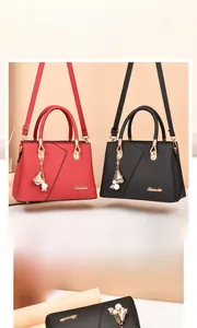 Detail of lychee textured leather handbags with flower charm and golden logo detail