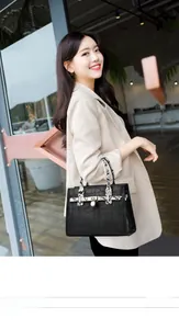 Close-up of black faux crocodile texture handbag with gold metal twist lock detail