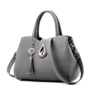 Elegant grey leather tote bag with gold teardrop clasp and tassel detail on white background