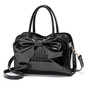 Glossy black patent leather handbag with large bow and crocodile embossed pattern