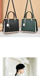 Detail of elegant handbag with gold lettering, contrast stitching and a white tassel charm