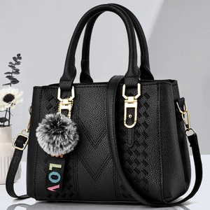 Elegant black lychee leather handbag with V-shaped stitching and faux fur pompom charm