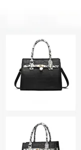 Detail view of black crocodile pattern tote bag with snakeskin handles and gold hardware