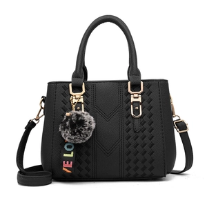 Chic black faux leather handbag for women featuring V-shaped stitching and plush pompom charm