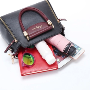 Black and burgundy leather handbag with large interior showing storage for daily items