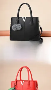Detail der Handtasche mit Leder-Litschi-Muster, V-Beschlag und Pelz-Pompon-Anhänger