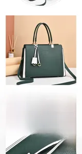 Detail of green leather tote bag with white side panels and gold metal hardware finish