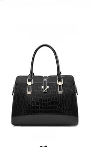 Vue de face d'un sac à main noir brillant à motif crocodile et détails dorés