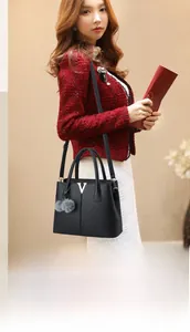 Detailansicht der schwarzen Handtasche aus Leder mit V-Metallverzierung und Plüsch-Anhänger