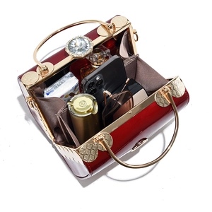 Glossy burgundy patent leather handbag with gold metal handle and crystal lock detail