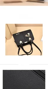 Detail of black litchi grain leather bag with gold bell pendant and tassel hardware