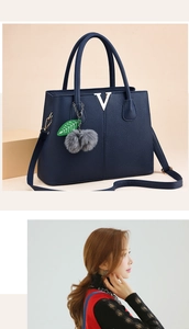 Detail der dunkelblauen Handtasche mit Litschi-Maserung, V-Logo und Plüschanhänger