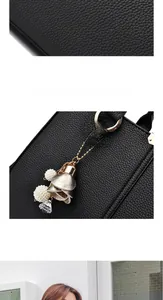 Detail of black lychee grain leather handbag featuring a floral pearl and crystal charm