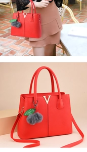 Detail der roten Handtasche mit Litschi-Maserung, Gold-V-Metall und Anhänger