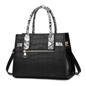 Chic black tote bag with crocodile texture and snake print handles on white background