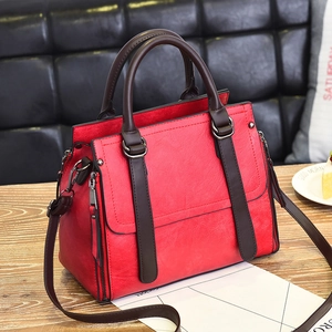 Fashionable red leather tote bag with brown handles on wooden table in a lifestyle setting