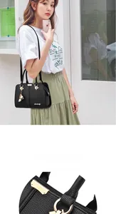 Close-up of litchi grain leather handle and golden metal buckle on black tote bag