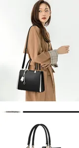Detail of a black leather handbag with white contrast side trim and golden hardware