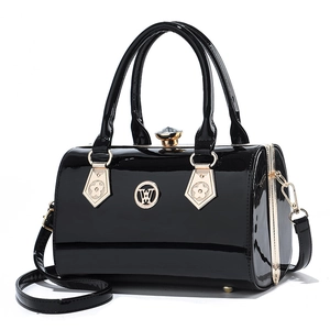 Fashionable black patent leather cylinder handbag with gold hardware and shoulder strap