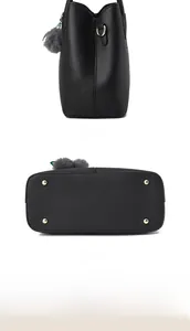 Detail der schwarzen Handtasche aus Litschi-Leder mit goldenen Füßchen und Plüschanhänger